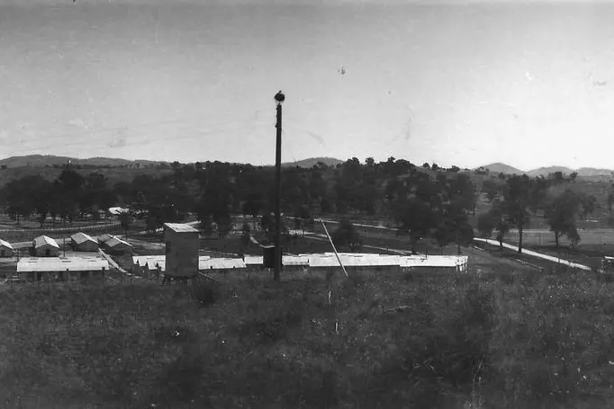 ITALIAN POW CAMP 5, WHOROULY EAST: A view of the fully constructed Myrtleford Camp 5 from Wangaratta Road, November 1943.  A searchlight and guard tower are visible in the foreground. Id:26890