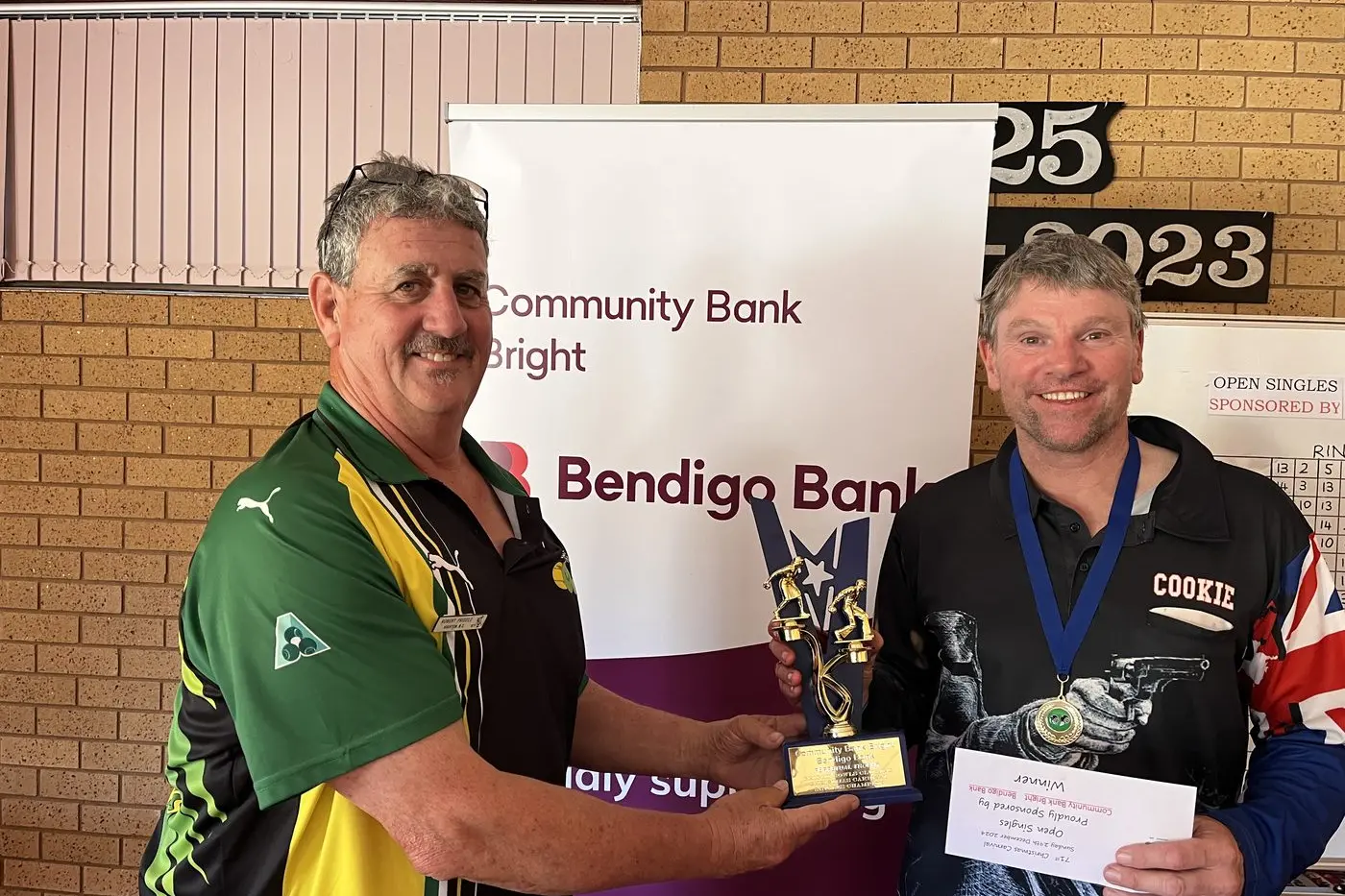 NEW CHAMPION: Last year\\'s winner of the singles event Rob Priddle (left) presents the trophy to winner Bradley Cooke from Middle Park Bowls Cl.ub