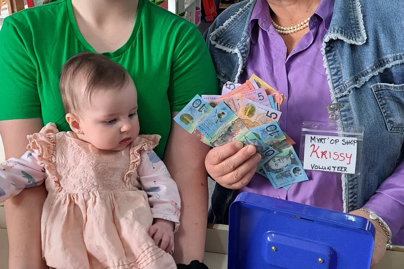 CLUTTER TURNED INTO CASH: Rachel Lovell\\'s new baby Faith with big sister Jenna Martin dropped by the Myrt\\' Op Shop and handed over their weekend garage sale wads to volunteer Krissy Dobbie. PHOTO: Rachael Lovell