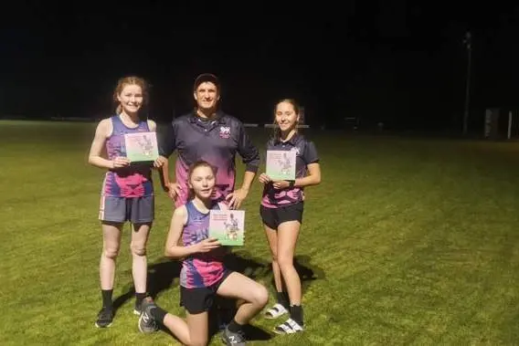 CREATING ART: Craig Dent (back, centre) has recently published his third children\\u2019s book, much to the excitement of his Alpine Lions youth girls (from left) Sophie Boyle, Taylah Power and (front) Shaye Power.