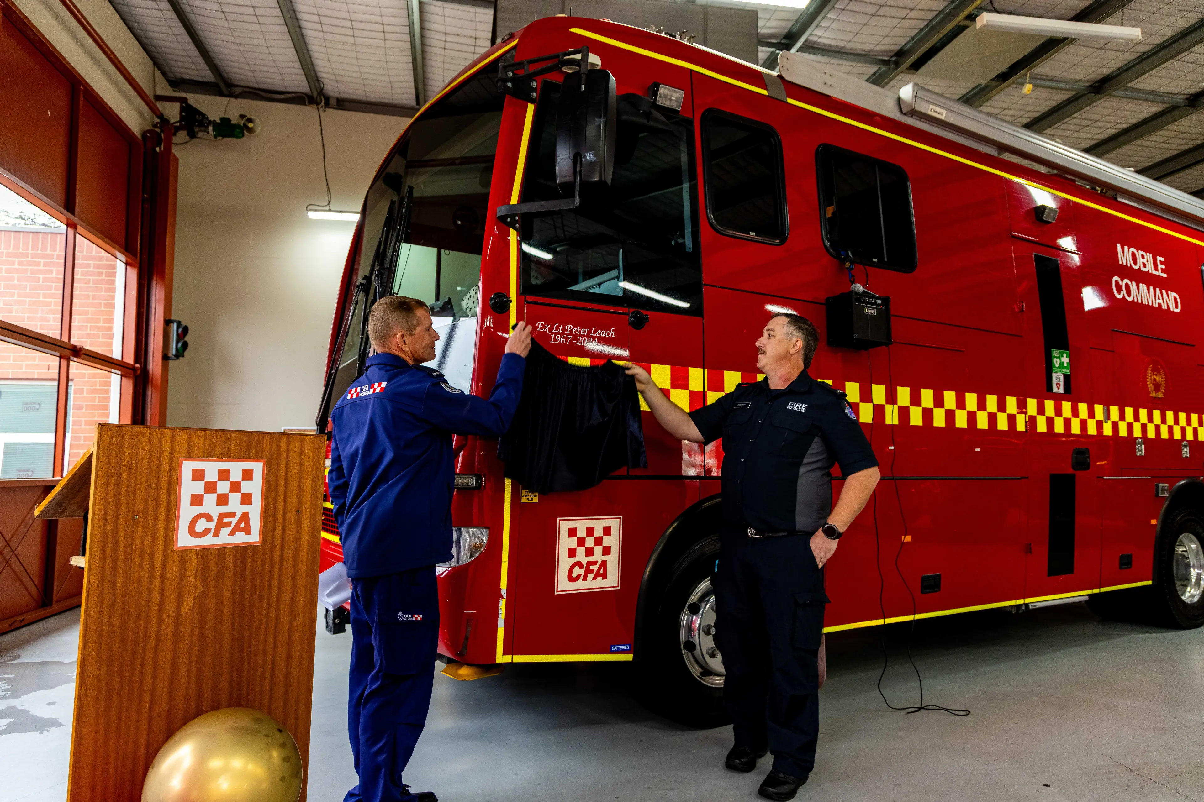 <p>COMMEMORATIVE UNVEILING: 1st Lieutenant Ian Lyons (left) and Philip Leach unveil a dedication to late brigade veteran, Peter Leach at the emergency service\\'s 150-year morning tea on Sunday 17 May. PHOTO: Paul McCully</p>\\n