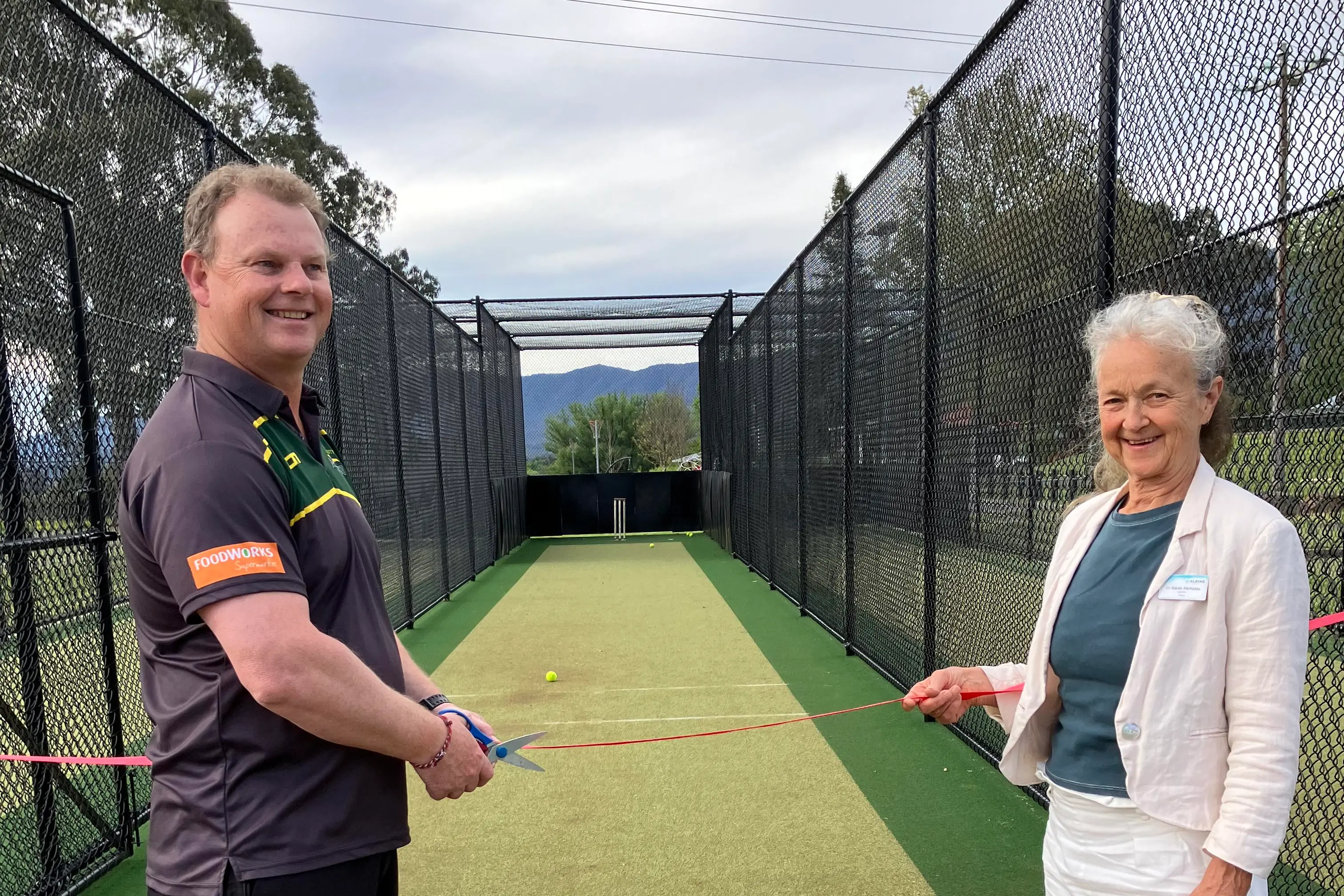 <p>OFFICIALLY OPENED: Mount Beauty United Cricket Club committee member Ross Wilson and Alpine Shire Mayor Sarah Nicholas cut the ribbon to officially open the new cricket nets at the Mt Beauty Recreation Reserve last Thursday evening. PHOTOS: Fay Mason </p>\\n